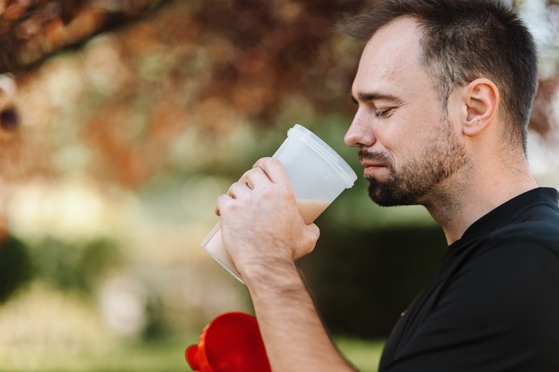 Man looking nauseous while drinking a mass gainer shake