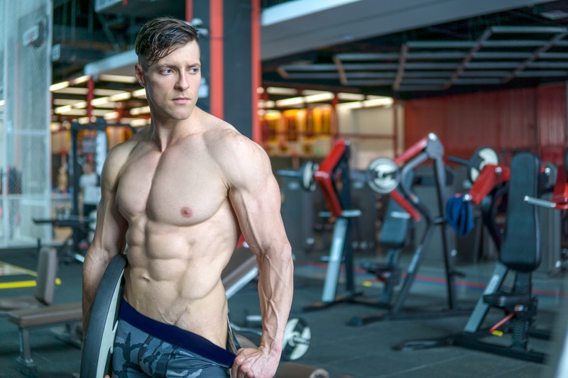 Lean bodybuilder with defined abs in a gym