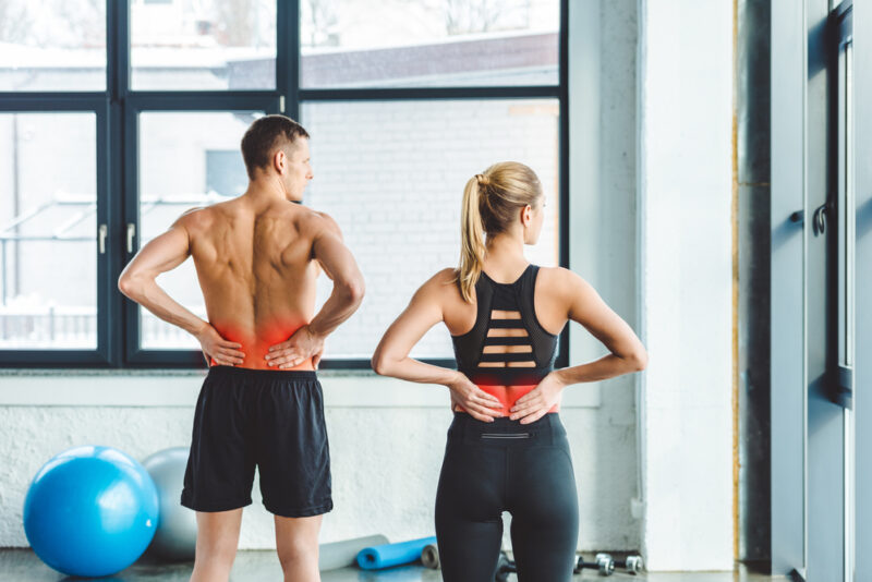 a man and a woman with lower back pain in the gym