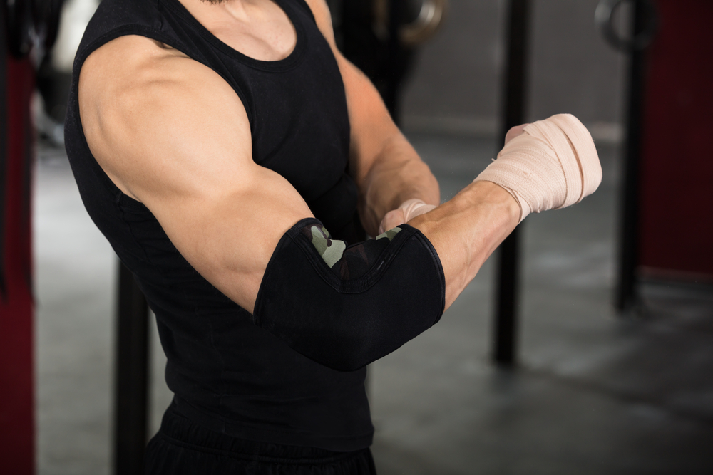 Man in the gym with elbow wrap to support his tennis elbow