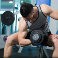 man with small arms doing concentration curls