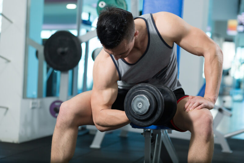 man with small arms doing concentration curls