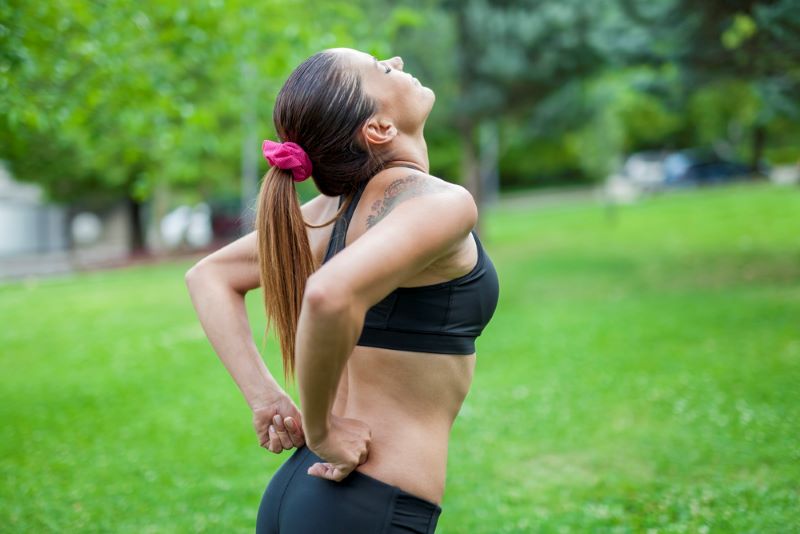 A fitness woman with lower back pain outside