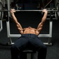 Topless man doing a bench press in the gym