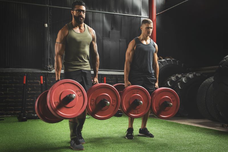 Two men doing farmers walk in a crossfit gym