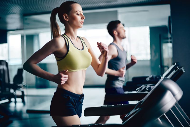 Woman and man running on treadmills in a gym