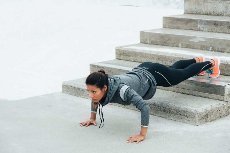Woman doing a decline push-up on some stairs