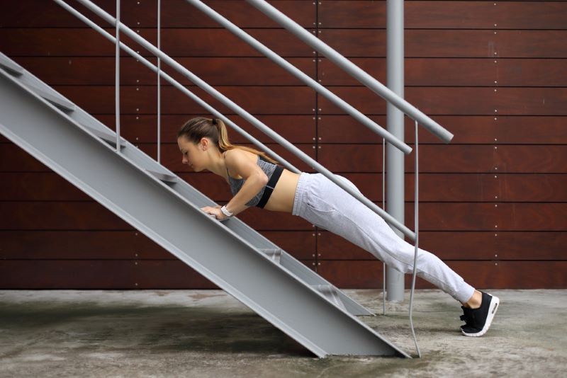 Woman doing an incline push-up on some stairs