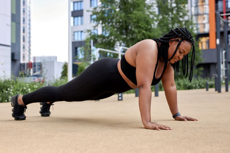 obese woman with fat arms doing a push-up outside