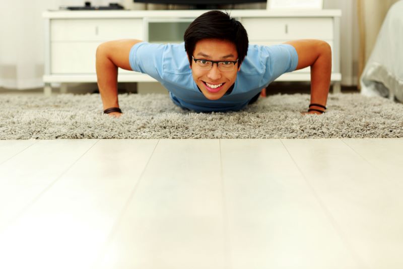 happy Asian man doing a push up on a carpet