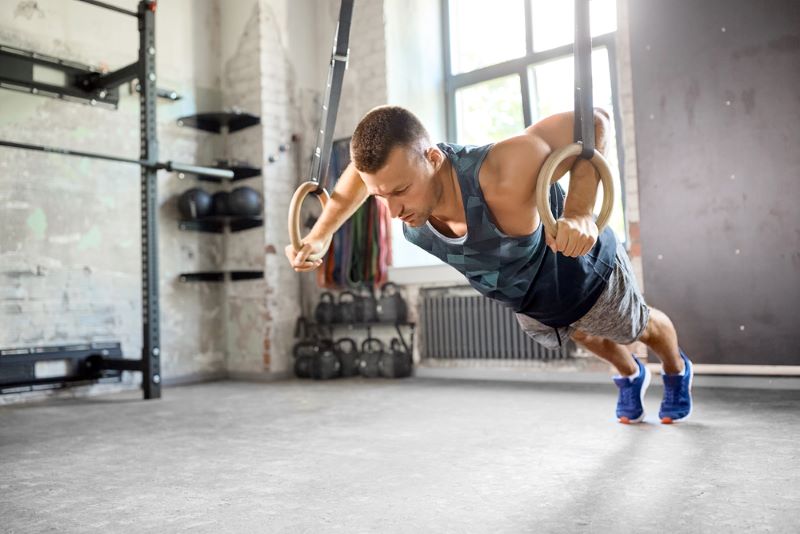 Man performing ring push-ups in a gym