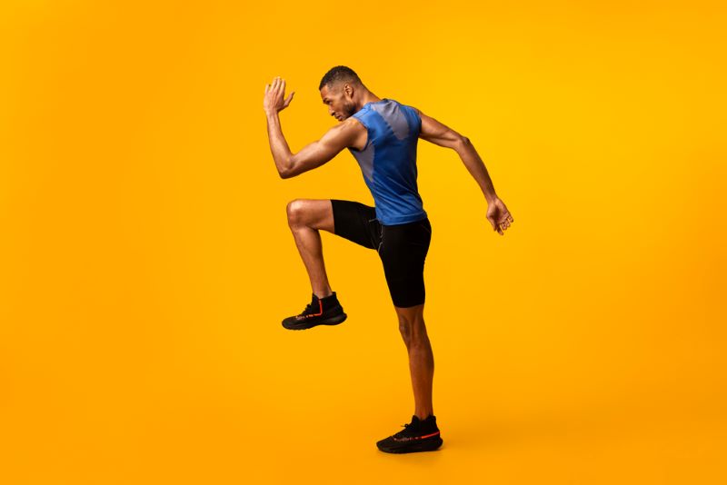 Man doing high knees in front of yellow background